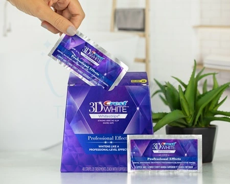 Box of Crest Professional Effects whitening strips with a pouch in front and a hand extracting another pouch.